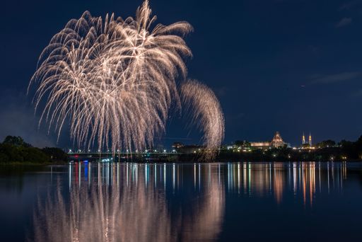 A beautiful view of fireworks in the night sky over the lake by the city