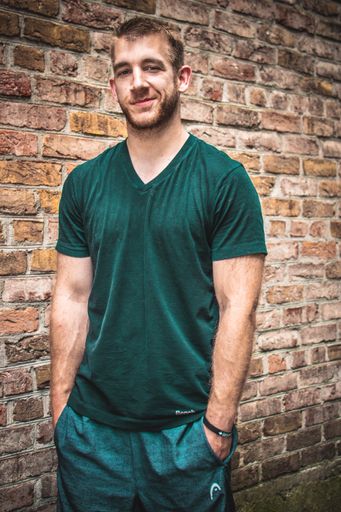 A vertical shot of a young Caucasian male standing against a brick wall