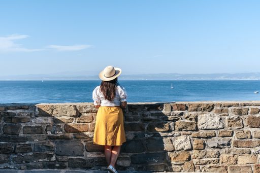 A back view of a young Caucasian woman admiring the view of the sea in Piran, Slovenia