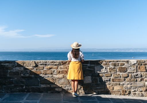 A back view of a young Caucasian woman admiring the view of the sea in Piran, Slovenia