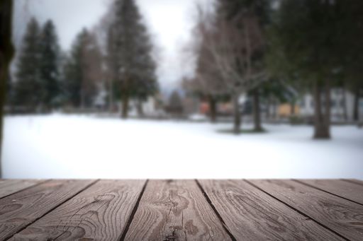 A selective focus shot of a snowy forest from a wooden surface