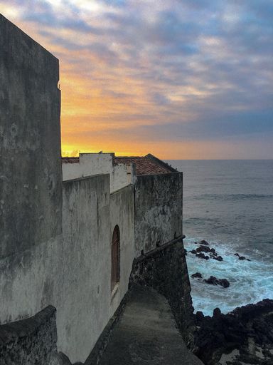 A vertical shot of stone buildings built on the cliff near the sea