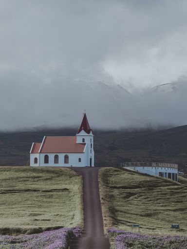 A vertical shot of the Ingjaldsholl church in Iceland under a gray cloudy sky