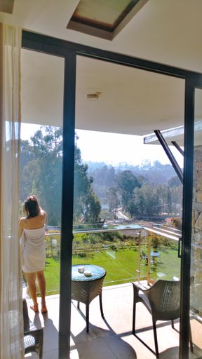 A table and chairs on a patio overlooking yard and a girl in towel enjoying the sunny day
