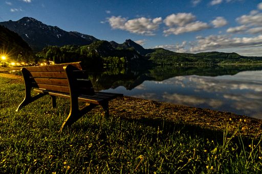 A beautiful shot of a seascape and a bench under the cloudy skies