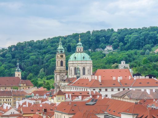 The St. Nicholas Church surrounded by greenery under a cloudy sky in Prague, the Czech Republic