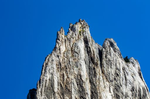 A tall lonely sharp cliff against the background of the blue sky