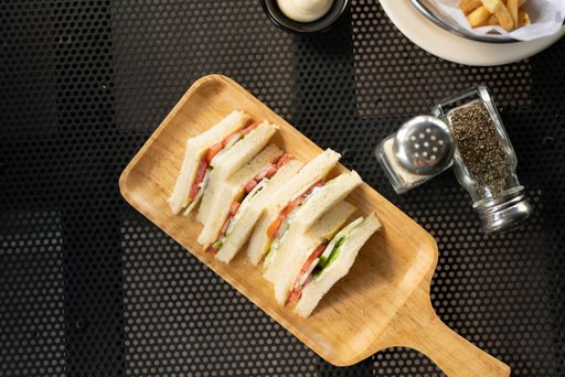 An overhead shot of toats with vegetables on a wooden tray near salt and pepper