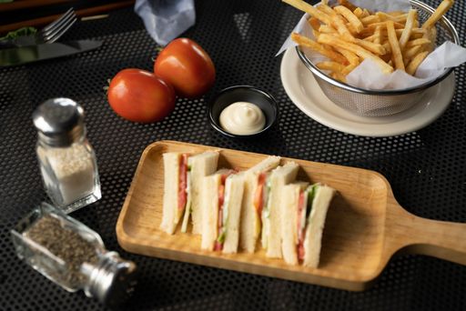 A high angle  shot of toats on a wooden tray near sauce and french fries