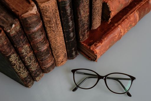 top view of an old leather cover books from the 19th century and glasses on a table