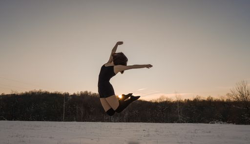 A young ballet dancer in training suit performing outdoors in wintertime