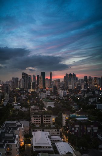 A vertical shot of city buildings under a cloudy sky at midnight