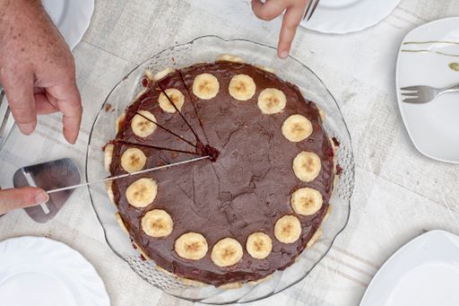 A top view shot of a chocolate cake with slices of bananas along the edges