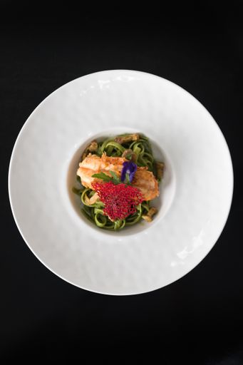 An overhead vertical shot of a dish with meat and noodles on a white plate