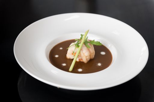 A close shot of a dish with meat, vegetables and a special sauce in a white plate