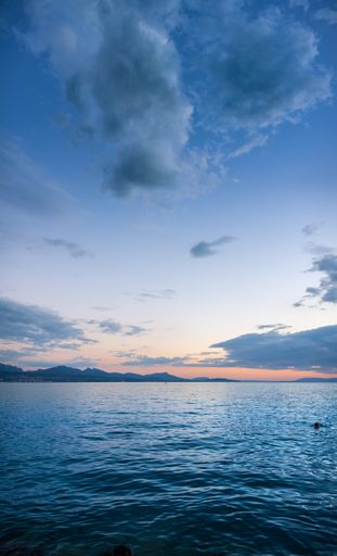 A vertical shot of a beautiful sea under a blue cloudy sky