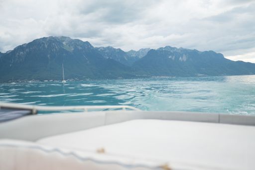 A beautiful shot from a boat of the sea with forested mountains in the distance under a cloudy sky