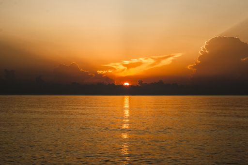 A beautiful shot of a red sun in an orange sky above the sea