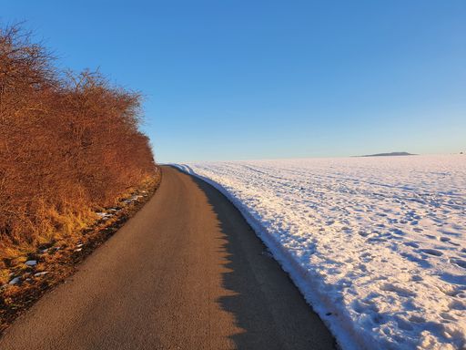 A scenic view of a road through a landscape covered with snow in winter
