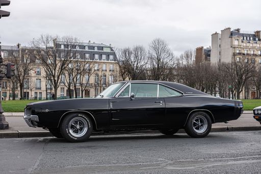 An old black Dodge Charger parked in the center of the city