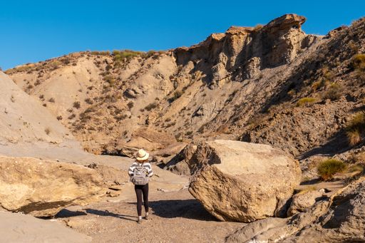 A young female Caucasian hiker with a backpack and straw hat at the Tabernas desert in Almeria, Andalusia, Spain