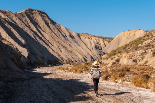 A young female Caucasian hiker with a backpack and straw hat at the Tabernas desert in Almeria, Andalusia, Spain