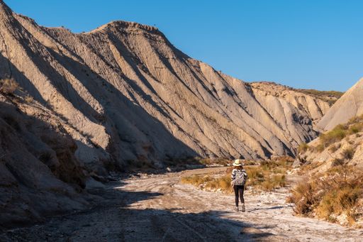 A young female Caucasian hiker with a backpack and straw hat at the Tabernas desert in Almeria, Andalusia, Spain