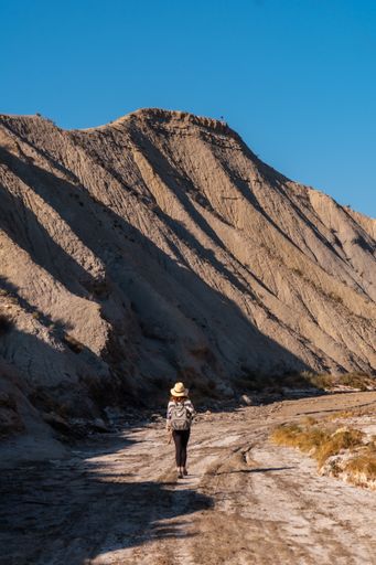 A young female Caucasian hiker with a backpack and straw hat at the Tabernas desert in Almeria, Andalusia, Spain