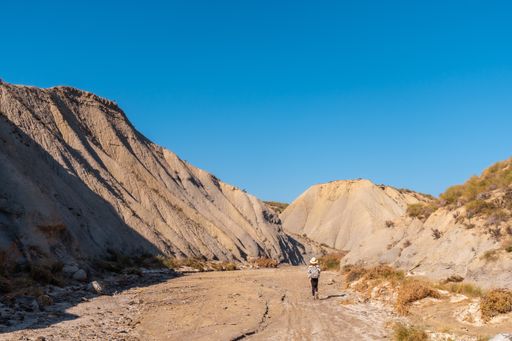 A young female Caucasian hiker with a backpack and straw hat at the Tabernas desert in Almeria, Andalusia, Spain