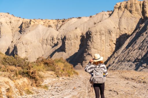 A young female Caucasian hiker with a backpack and straw hat at the Tabernas desert in Almeria, Andalusia, Spain