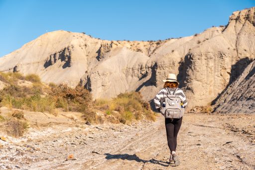 A young female Caucasian hiker with a backpack and straw hat at the Tabernas desert, Almeria, Andalusia, Spain