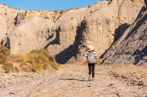 A young Caucasian female hiker with a backpack and straw hat in the desert of Tabernas, Almeria, Spain