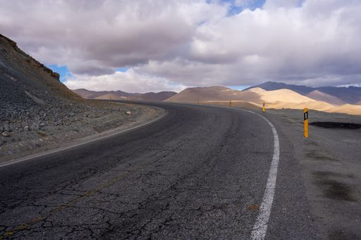 A beautiful shot of a curved emptyroad in the middle of a dry plain field