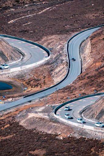 A vertical shot of asphalt roads in a rural area surrounded by dry vegetation