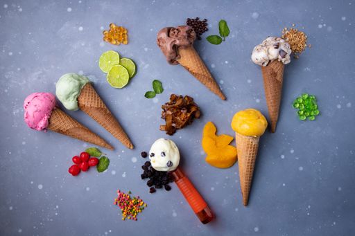 A top view of ice cream of different flavors in waffle cones with candies and fruits