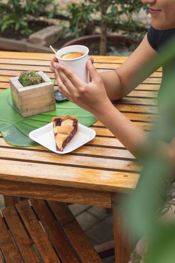 A vertical shot of a Hispanic young female taking enjoying her tea in a park