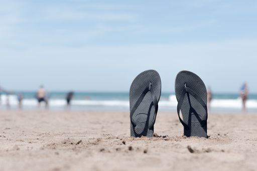 A pair of flip flops standing upright on the beach