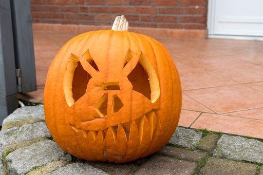 An orange pumpkin with a face on a concrete surface for Halloween