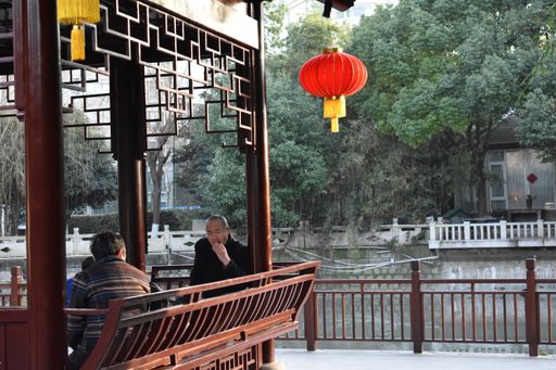 A view of people sitting in a typical Asian alcove in the park in Shanghai, China