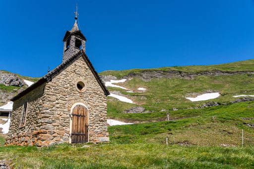 A small white church on top of a grassy hill