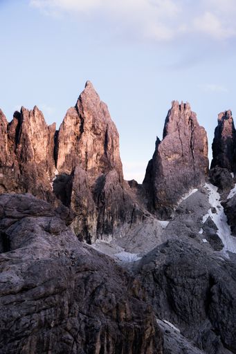A vertical shot of big rocks on top of a mountain with a clear sky in the background