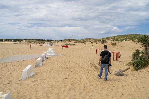 A male photographer walking through a beach under a cloudy sky at daytime in Andalusia, Spain