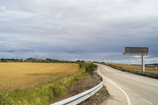 A road surrounded by field covered in the grass under a cloudy sky at daytime in Andalusia, Spain