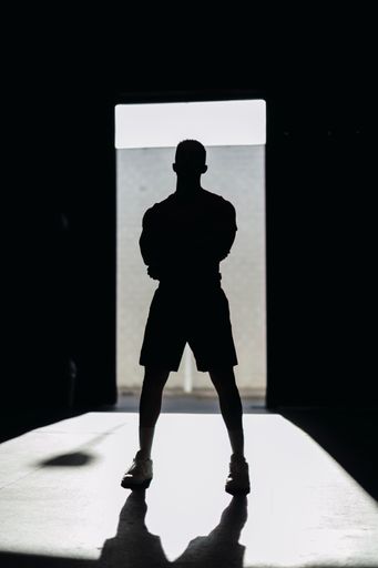 A vertical shot of a silhouette of a powerful male standing in a doorway