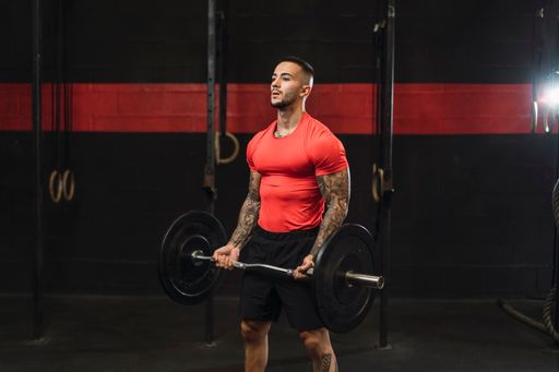 An athlete working out in the gym in a red workout shirt