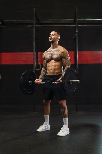 A tattooed athlete working out in the gym shirtless