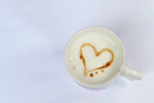 A cup of cappuccino with a heart shape isolated on white background