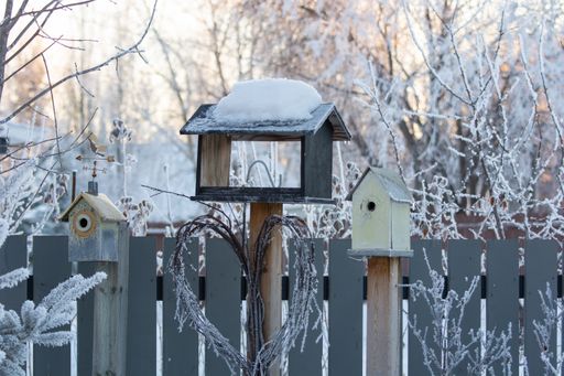 Three birdhouses of different sizes during winter with snow covered trees