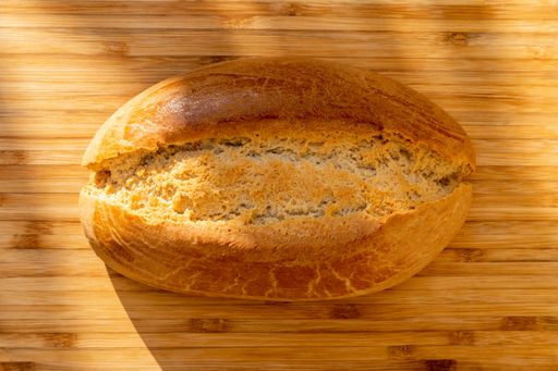 An overhead shot of sourdough bread on a light wooden cutting board under the sunlight