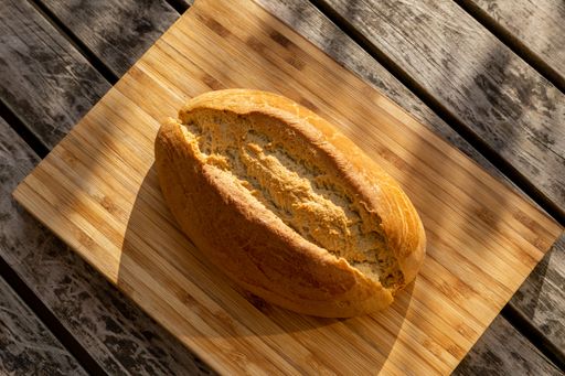 A high angle shot of sourdough bread on a light wooden cutting board on a darker wood surface